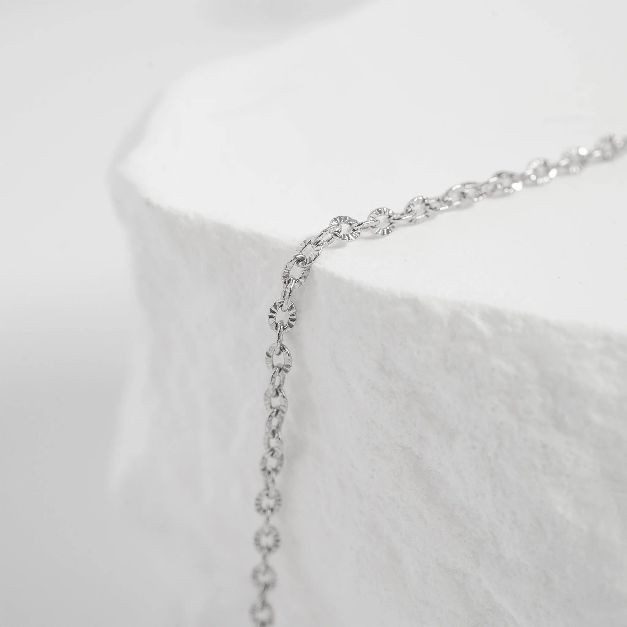 Crimped oval link chain necklace in silver tone with delicate design.