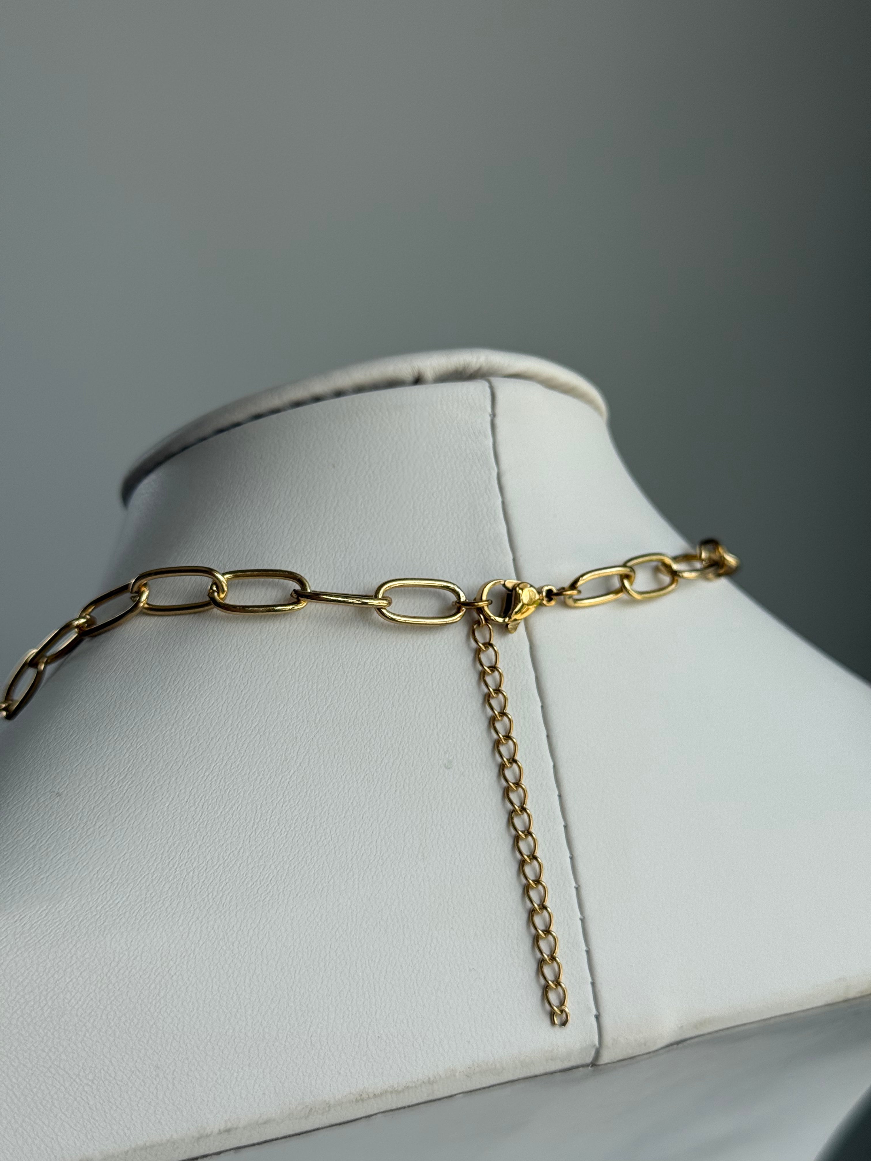 Signature Paperclip chain necklace in gold-tone metal on a white display bust