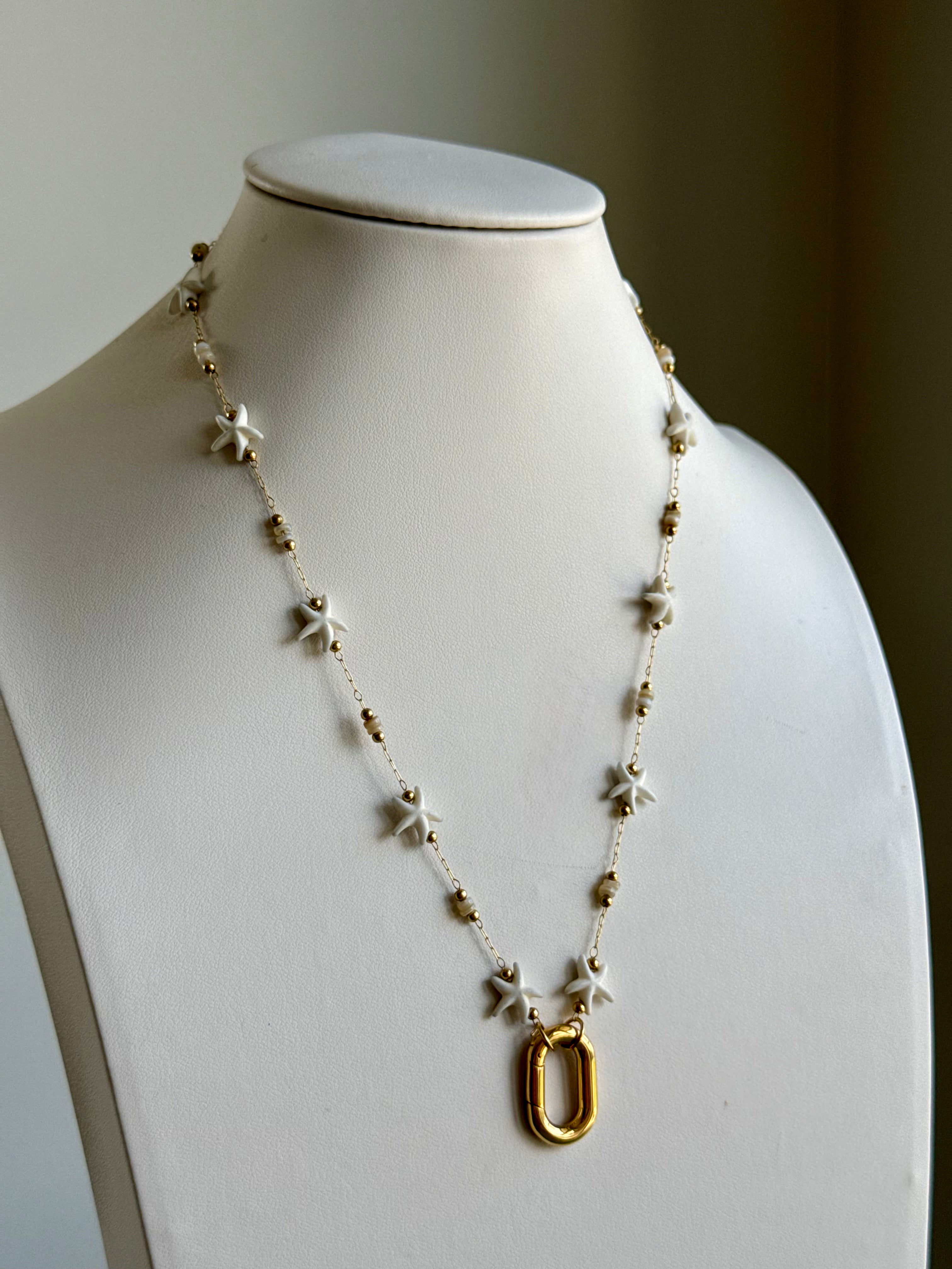 Signature Chain / Starfall necklace by From Juniper With Love; gold-tone chain with white star beads and a gold oval pendant.