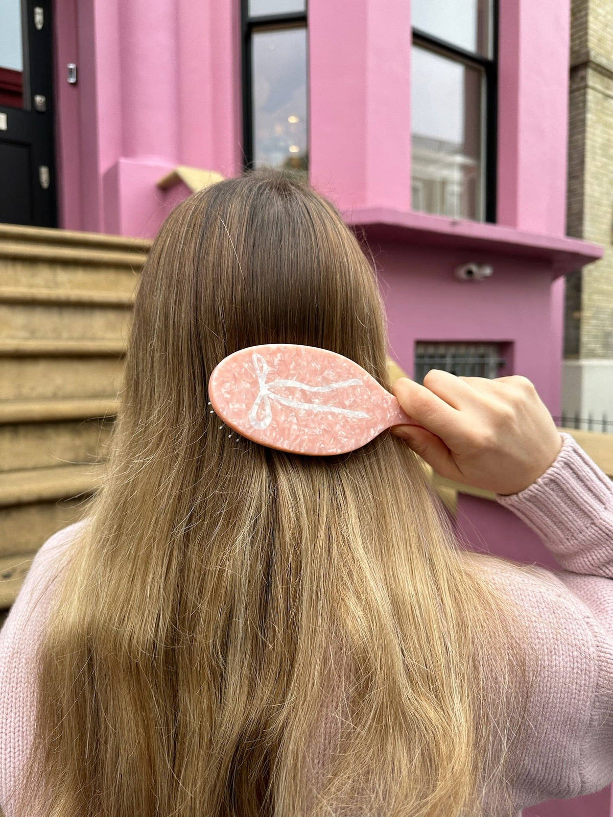 Hand-painted ballet bow hairbrush by Solar Eclipse, pink marble handle on long brown hair.