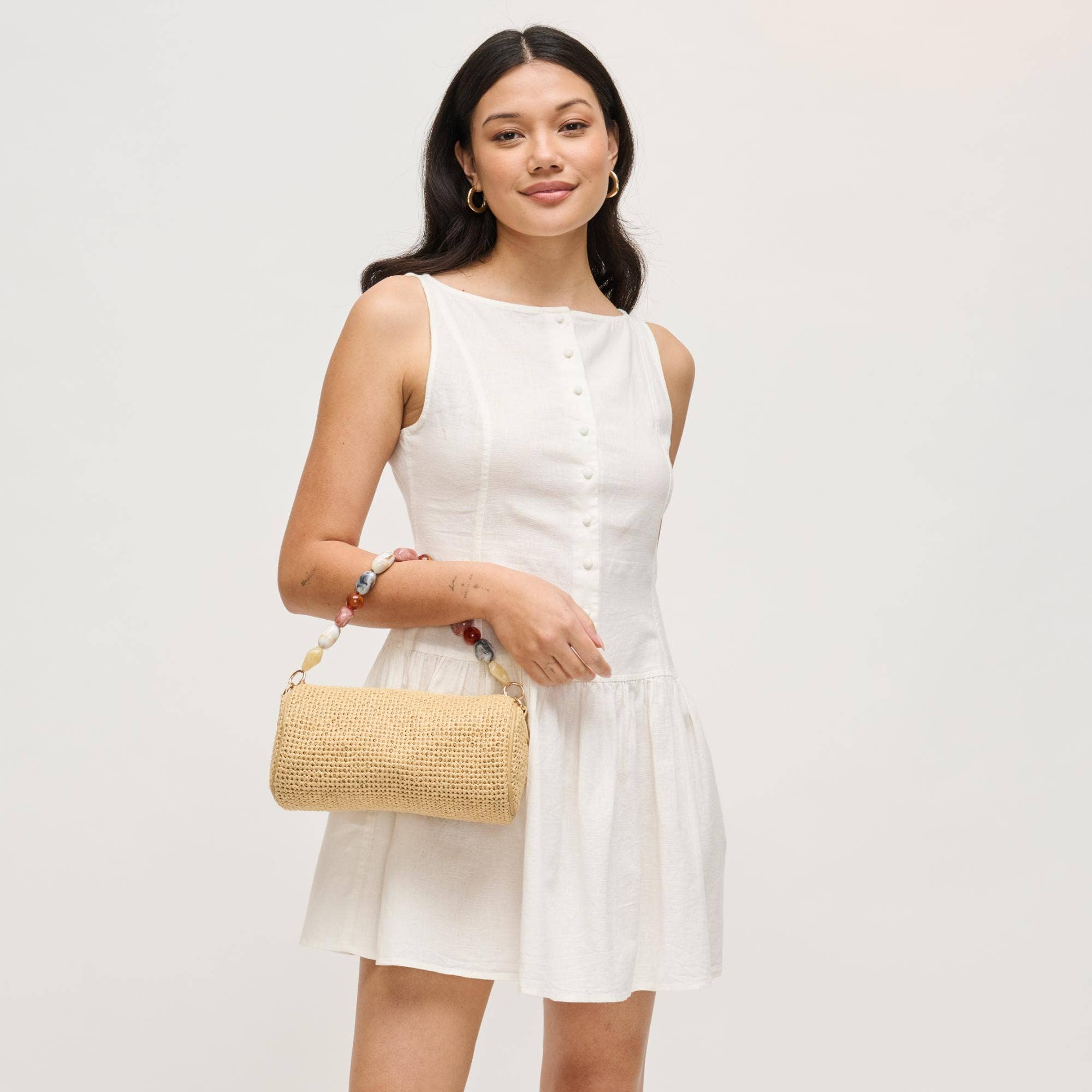Rachel straw clutch by Urban Expressions in natural color, carried by a model.