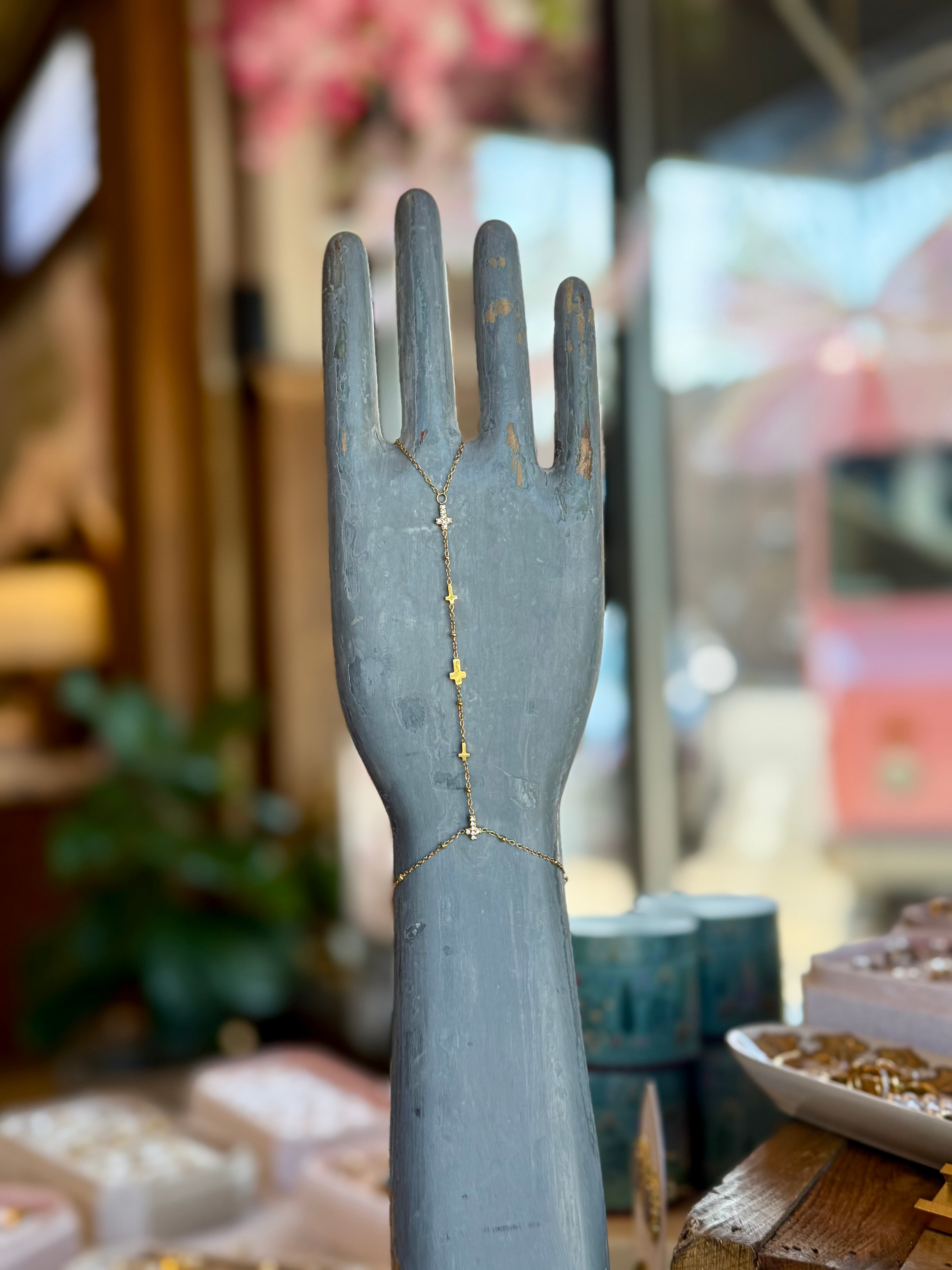 Sacred Hand Chain bracelet in gold with cross charms displayed on a distressed blue hand