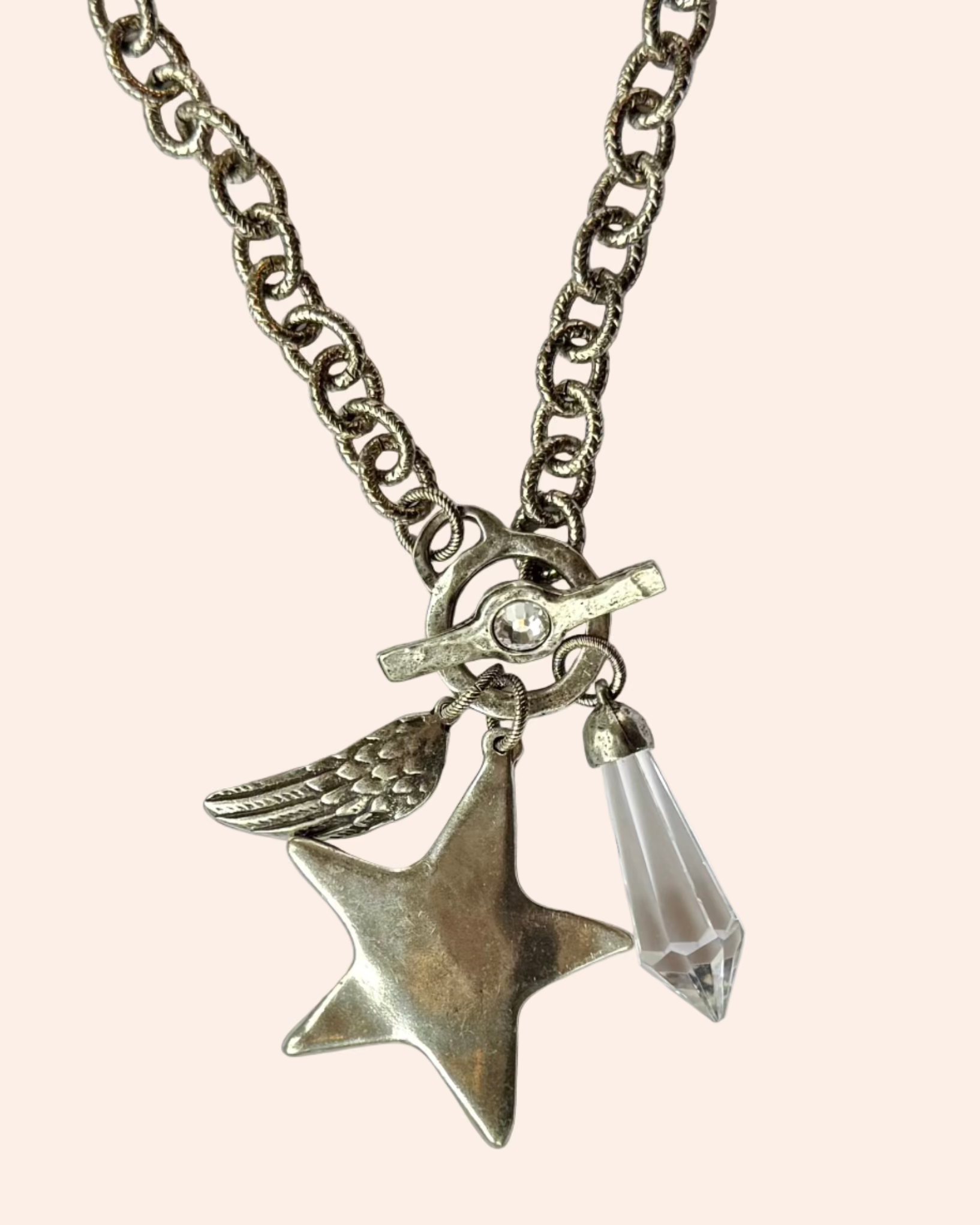 Silver necklace with star and teardrop pendant on a white background