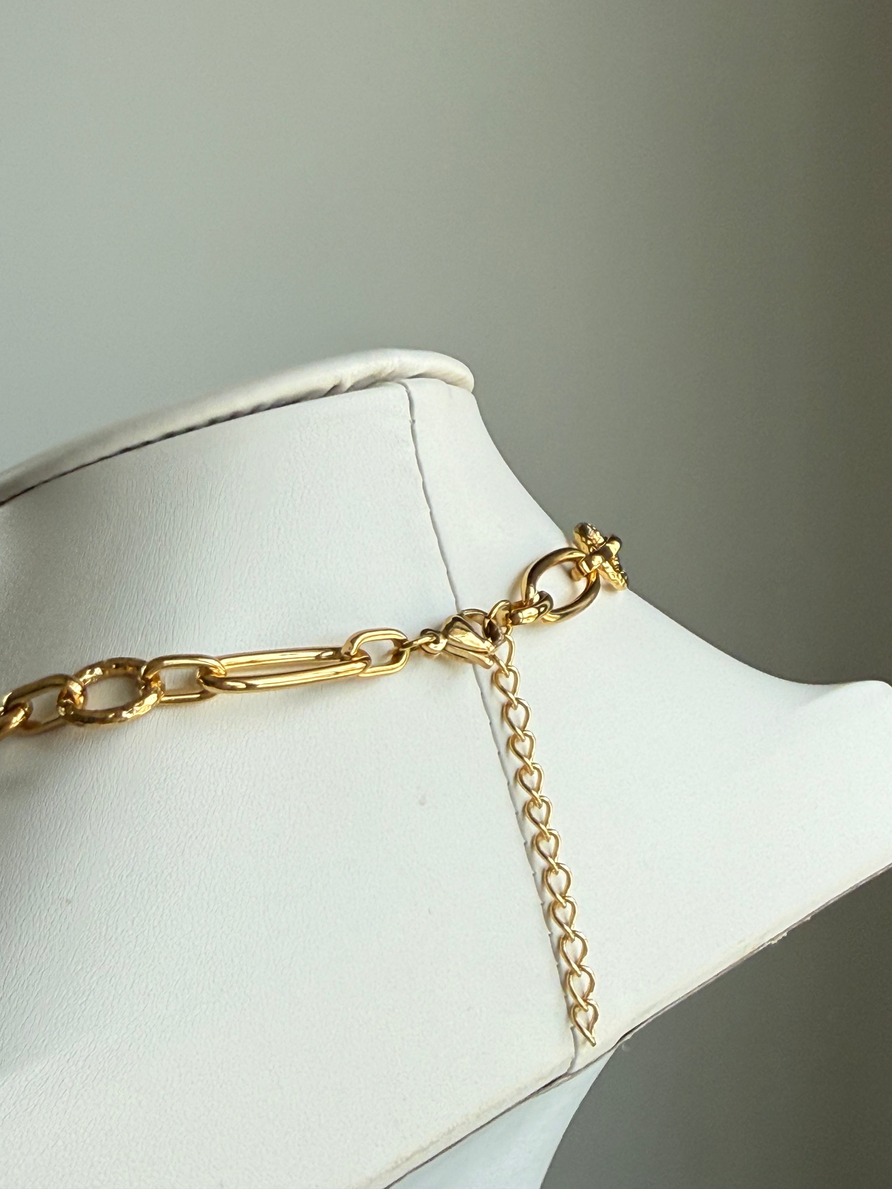 Signature Chain / Textured Muse necklace in gold-tone metal with textured links on a white display.