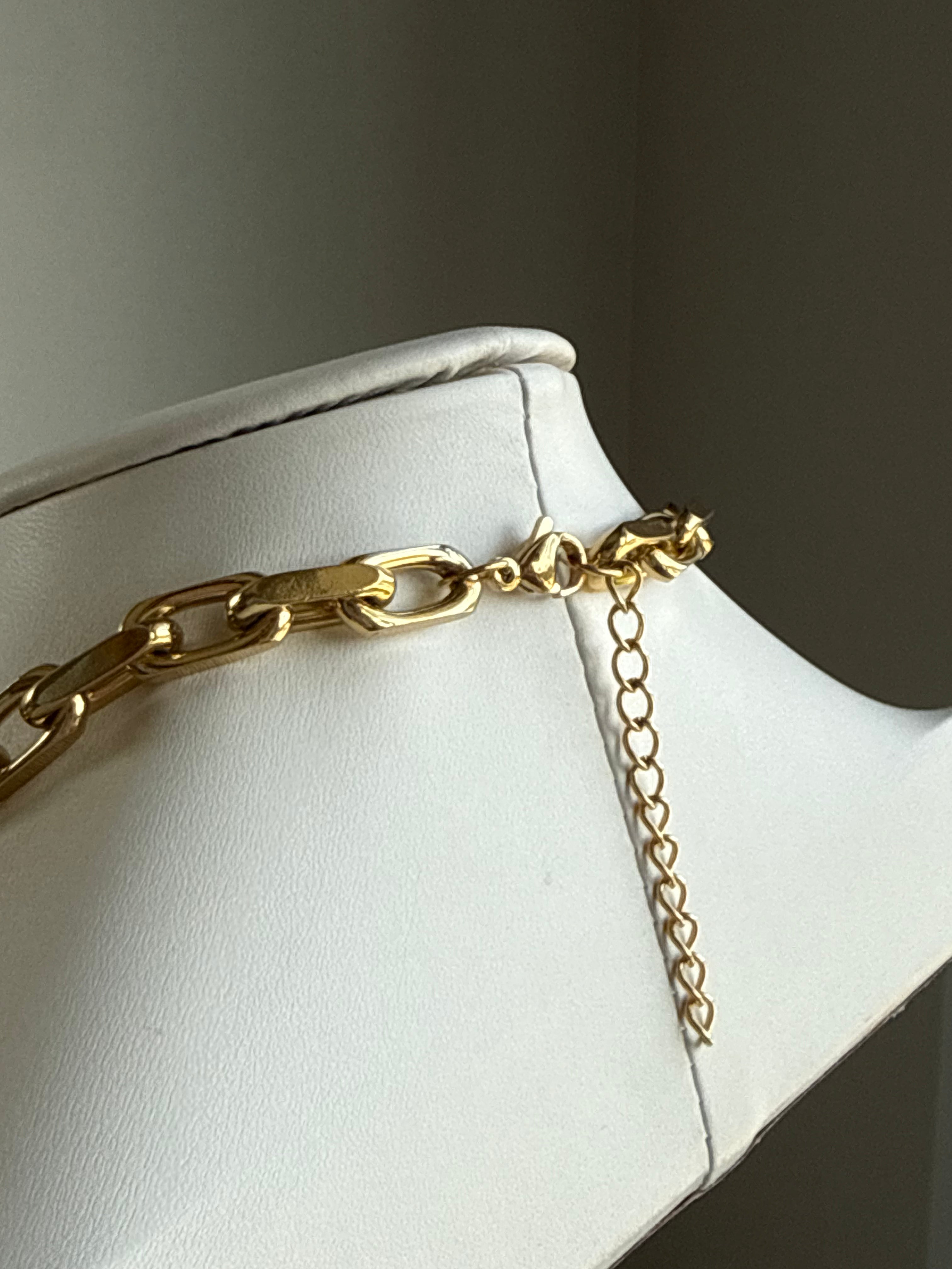 Signature Chain Chunky Paperclip necklace with gold-tone metal links on a white display bust, close-up.