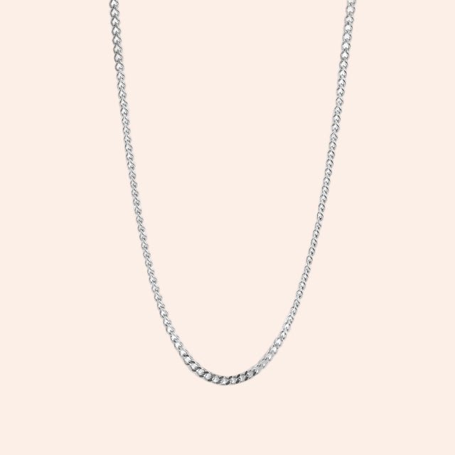 Curb chain necklace in silver on white background; close-up view