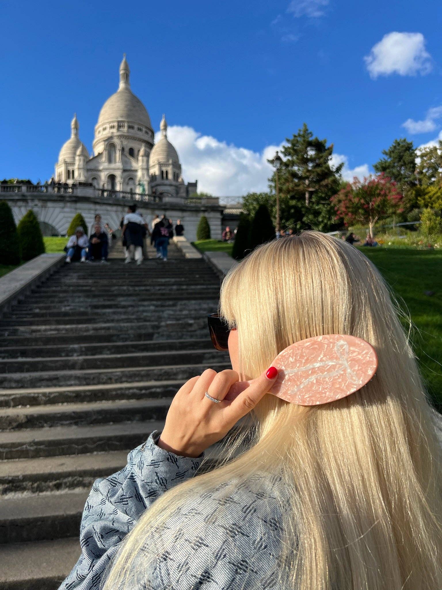 Hand-painted ballet-bow hair brush; pink marbled handle held by a blonde outdoors near grand stairs