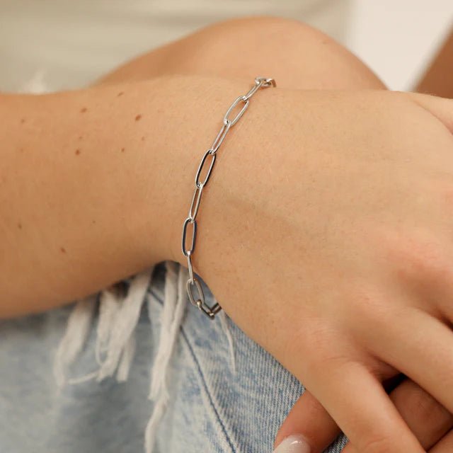 Paperclip chain bracelet in silver worn on a denim-clad wrist
